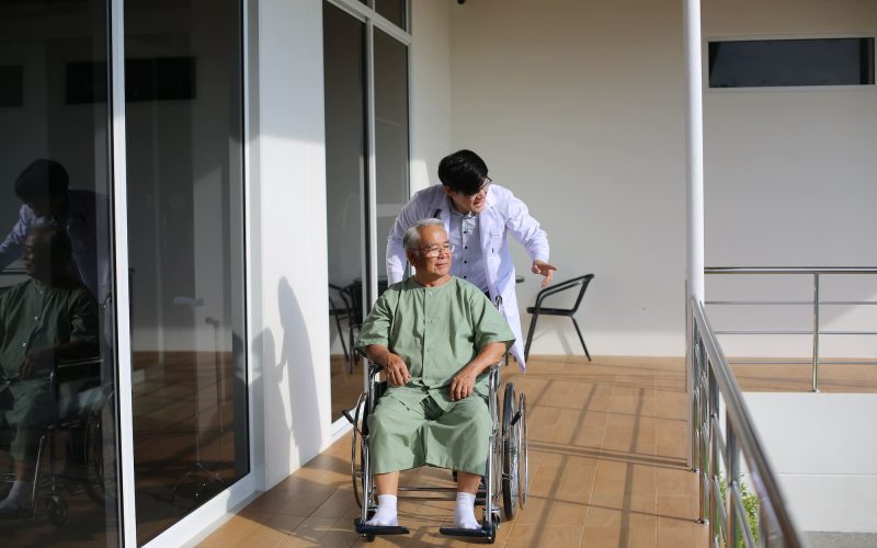 caretaker-helping-senior-man-with-disability-at-checkup-visit.jpg